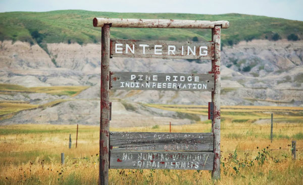 A wooden sign that reads "ENTERING PINE RIDGE INDIAN RESERVATION"